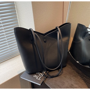 Detail shot of black pebbled leather tote bag with V-cut design and magnetic closure