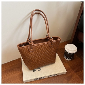 Detail of brown woven tote bag featuring herringbone pattern and knotted handle accents