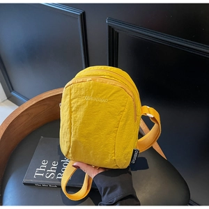 Détail d'un sac à dos en nylon gingembre avec logo brodé et compartiment zippé avant