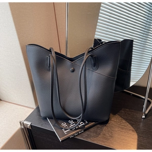 Close-up of black lychee grain leather tote bag with V-cut opening and button detail
