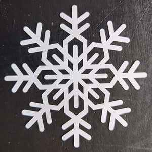 Detailed close-up of a white hollow snowflake coaster with intricate cutout patterns