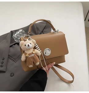 Detail of khaki PU leather satchel with silver turn-lock and cute plush bear charm