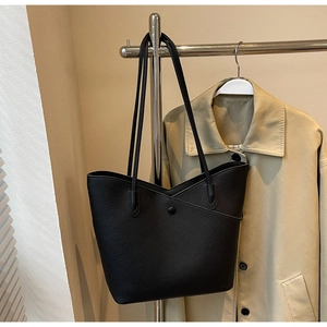 Detail of black pebbled leather tote bag with unique cross-overlap closure and snap button