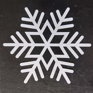 Detailed view of white hollowed snowflake coaster on a contrasting black background