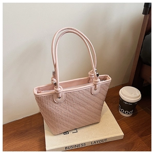 Detailed view of pink woven bucket bag featuring knot decorative accents and long straps
