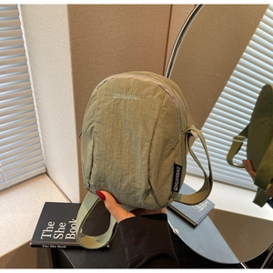 Détail d'un mini sac bandoulière en nylon vert olive avec broderie blanche de la marque