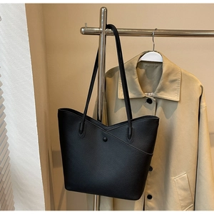 Detail of black lychee-textured tote bag with V-shaped closure and magnetic snap button