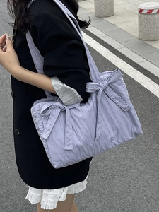 Lavender pleated nylon bucket bag with large bow detail shown in an urban street setting