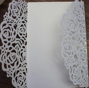 Close-up of white laser-cut wedding invitation cover with elegant rose flower pattern