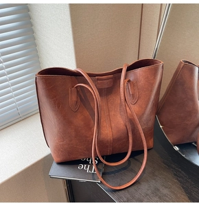 Close-up of vintage brown leather tote bag with fine stitching and soft natural texture