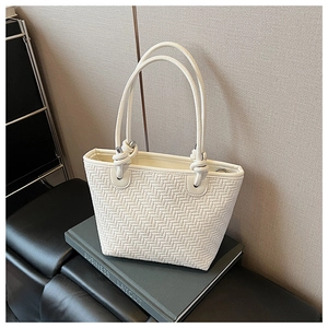 Detail view of white woven tote bag with knotted handle texture on a decorative book