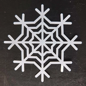 Macro shot of white hollow snowflake paper coaster with precise laser-cut patterns