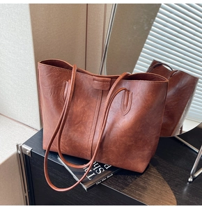 Detail view of large brown vintage tote bag with fine wrinkled texture and slim straps
