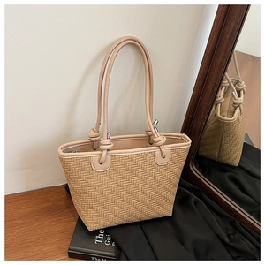 Detail of the woven texture and knotted handle on a beige tote bag for women