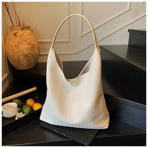 Detailansicht einer cremefarbenen Canvas-Tasche mit Fischgrätenmuster und Lederriemen