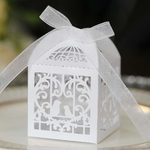 Detail of white laser-cut favor box with pearlescent finish and organza ribbon bow