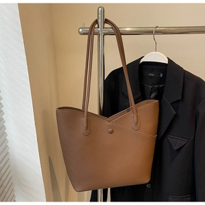 Close-up of brown pebbled leather tote bag with V-cut opening and sleek dual shoulder straps