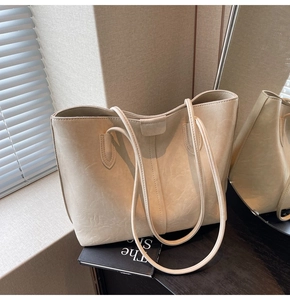 Detail of cream white tote bag featuring vintage cracked leather texture and thin strap
