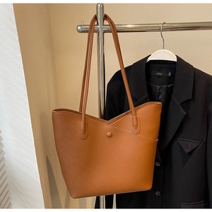 Detail view of caramel pebbled leather tote bag with V-shaped overlay and decorative buckle