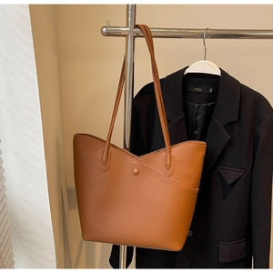 Detailed view of brown lychee leather tote bag with unique V-shaped asymmetric top design