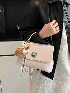 Retro cream-colored square handbag with adjustable strap and teddy bear charm