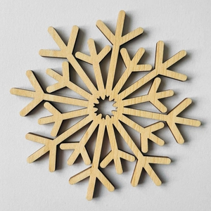 Macro detail of laser-cut snowflake wooden coaster with natural grain and scorched edges
