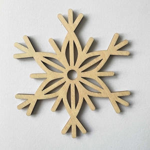 Macro detail of laser-cut wooden snowflake coaster with natural grain and precise edges