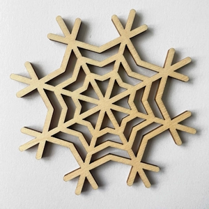 Detail of laser-cut wooden snowflake coaster with intricate geometric hollow patterns