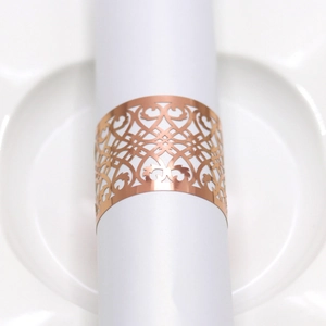 Macro view of rose gold hollow napkin ring with laser-cut heart patterns on a white napkin