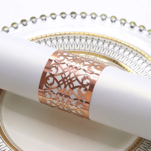 Close-up of rose gold hollow napkin ring with elegant European pattern on white porcelain plate