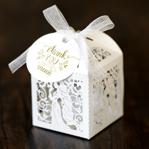 Detailed laser-cut floral pattern on a white candy gift box with a white ribbon bow