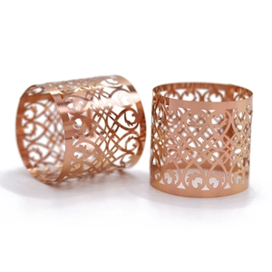 Detail of rose gold napkin rings with intricate hollowed-out heart and scroll patterns