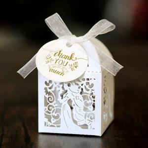 Close-up of white laser-cut candy box with elegant ribbon and thank you tag