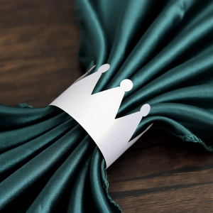 Detail of elegant white crown paper napkin ring with satin napkin on dark wood