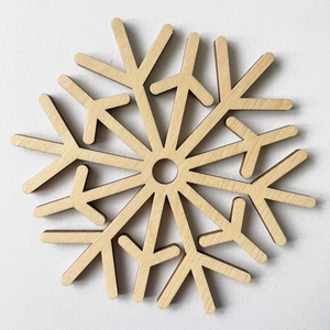 Macro shot of laser-cut wooden snowflake coaster showing natural grain and precise edges