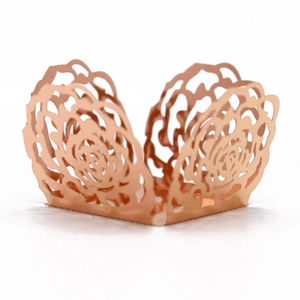 Macro shot of rose gold laser-cut floral cupcake wrappers with metallic reflective finish