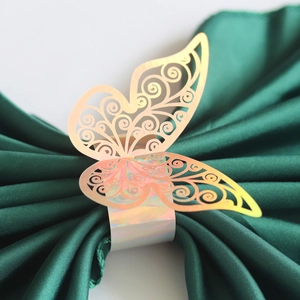 Macro view of a laser-cut butterfly napkin ring with iridescent gold finish on satin fabric