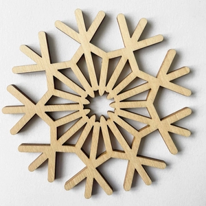 Macro view of laser-cut snowflake wooden coaster showing natural wood grain and details