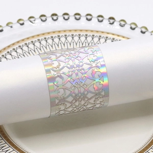 Macro detail of holographic laser-cut vine patterns on rose gold napkin ring