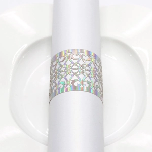 Detail of laser-cut rose gold napkin ring with intricate pattern on white napkin