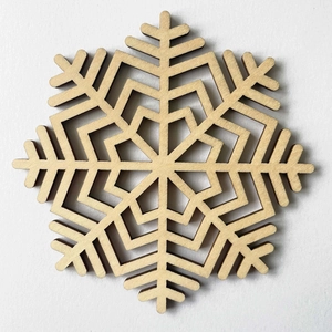 Close-up of laser-cut wooden snowflake coaster with natural wood grain and charred edges