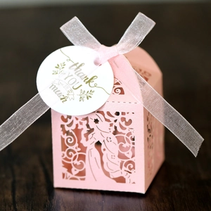 Macro view of pink laser-cut gift box with floral patterns and a thank you tag