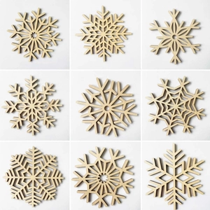 Set of 9 laser-cut wooden snowflake coasters with intricate geometric patterns and natural wood