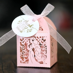 Detail of pink laser-cut gift box with floral pattern, pink ribbon and thank you card