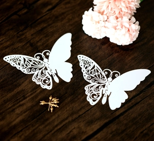 Macro detail of laser-cut white butterfly cards with intricate hollow vine patterns