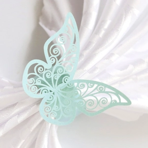 Macro detail of laser-cut light blue butterfly napkin ring on white silk background