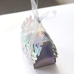 Macro detail of laser-cut butterfly candy box with iridescent finish and white silk ribbon