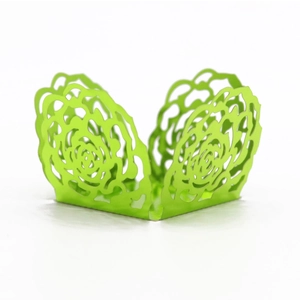 Detail view of laser cut emerald green rose pattern cupcake wrapper on white background