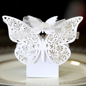 Detail of laser-cut white butterfly favor box with rose patterns and organza ribbon