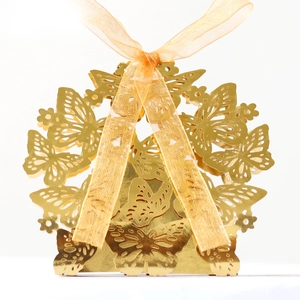 Macro shot of gold laser-cut butterfly wedding candy box with a silk ribbon bow